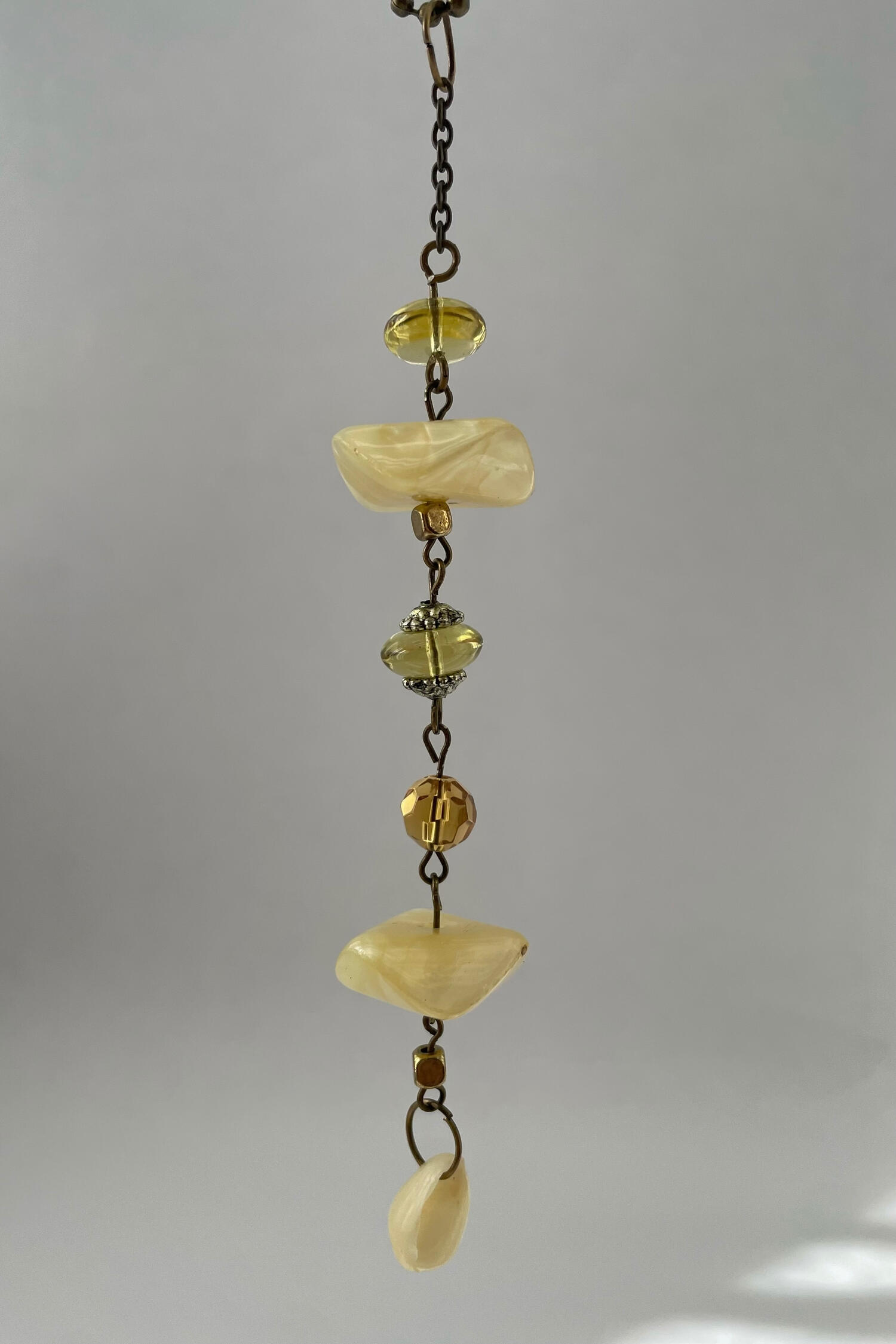 Sunlit Shoals Handmade rear-view mirror charm featuring antique bronze hardware, soft cream and amber-toned beads, and a small shell suspended against a neutral background.